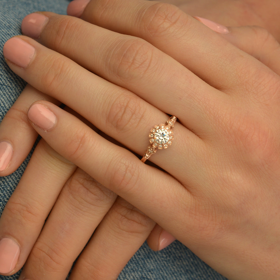 round halo vintage inspired engagement ring in rose gold  in a hand