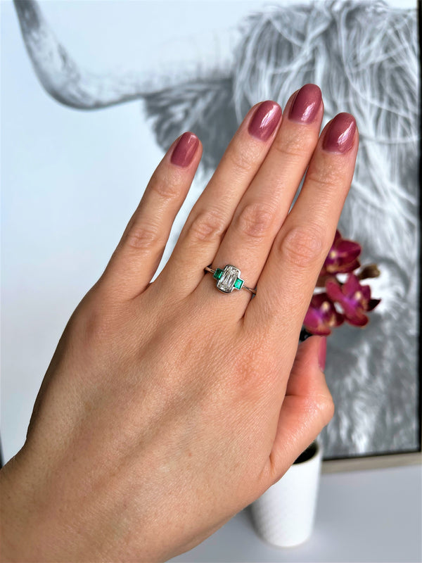 hand with bezel engagement ring with clolombian emeralds