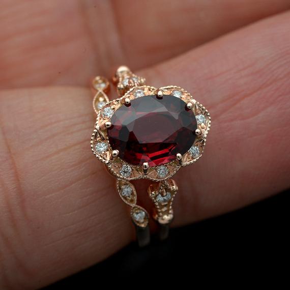 red garnet oval halo rose gold engagement ring set in hand
