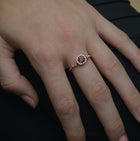 rose gold cushion halo engagement ring red garnet red center in a hand