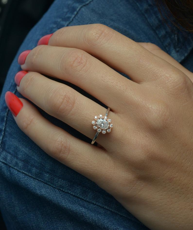 oval natural diamond flower halo two tone ring in a hand